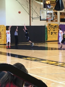 Freshman Flyer #20 takes a shot out in 3-point territory as an opponent makes an attempt to block the shot.