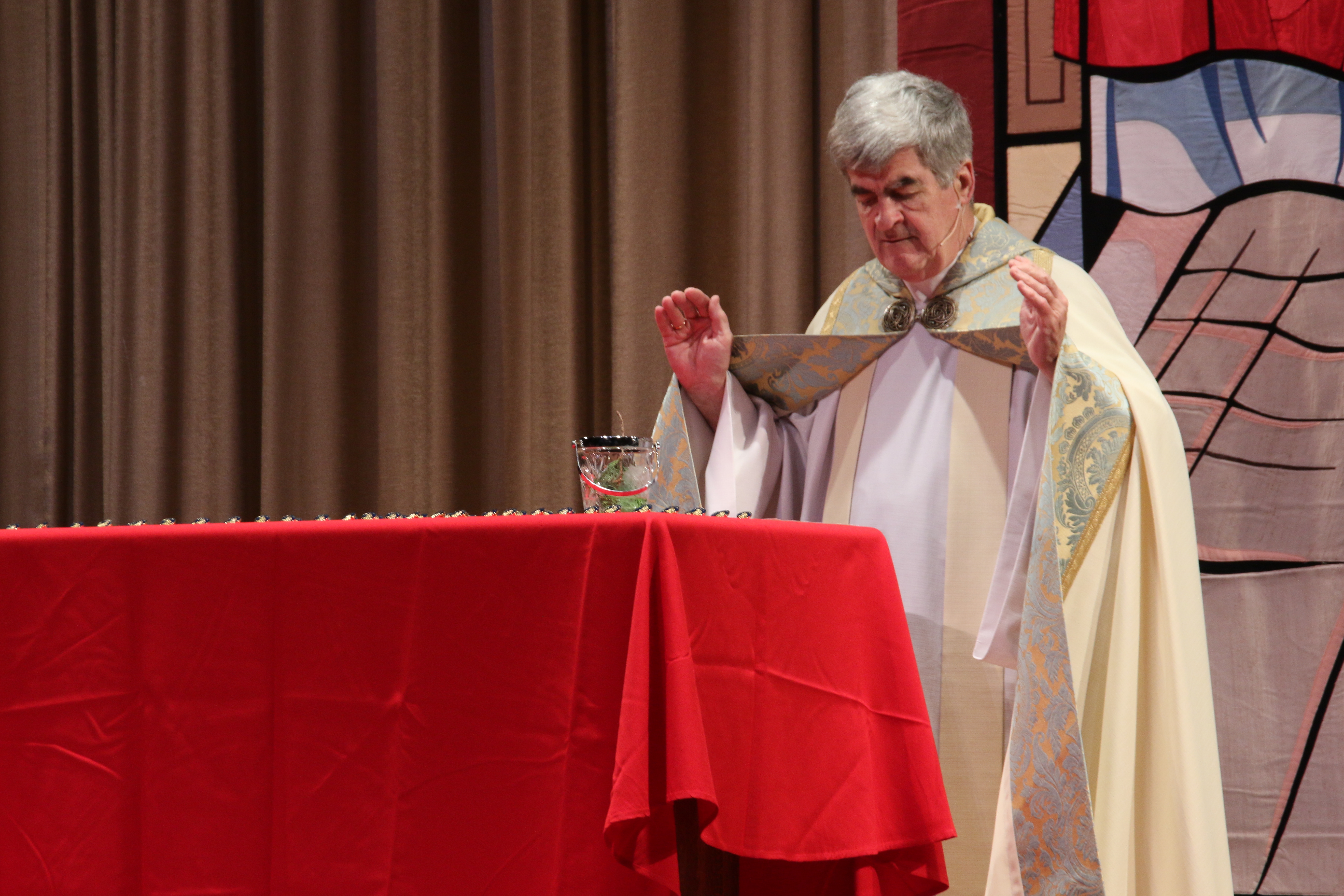 Fr. Garrett Long blesses Sodality pins.